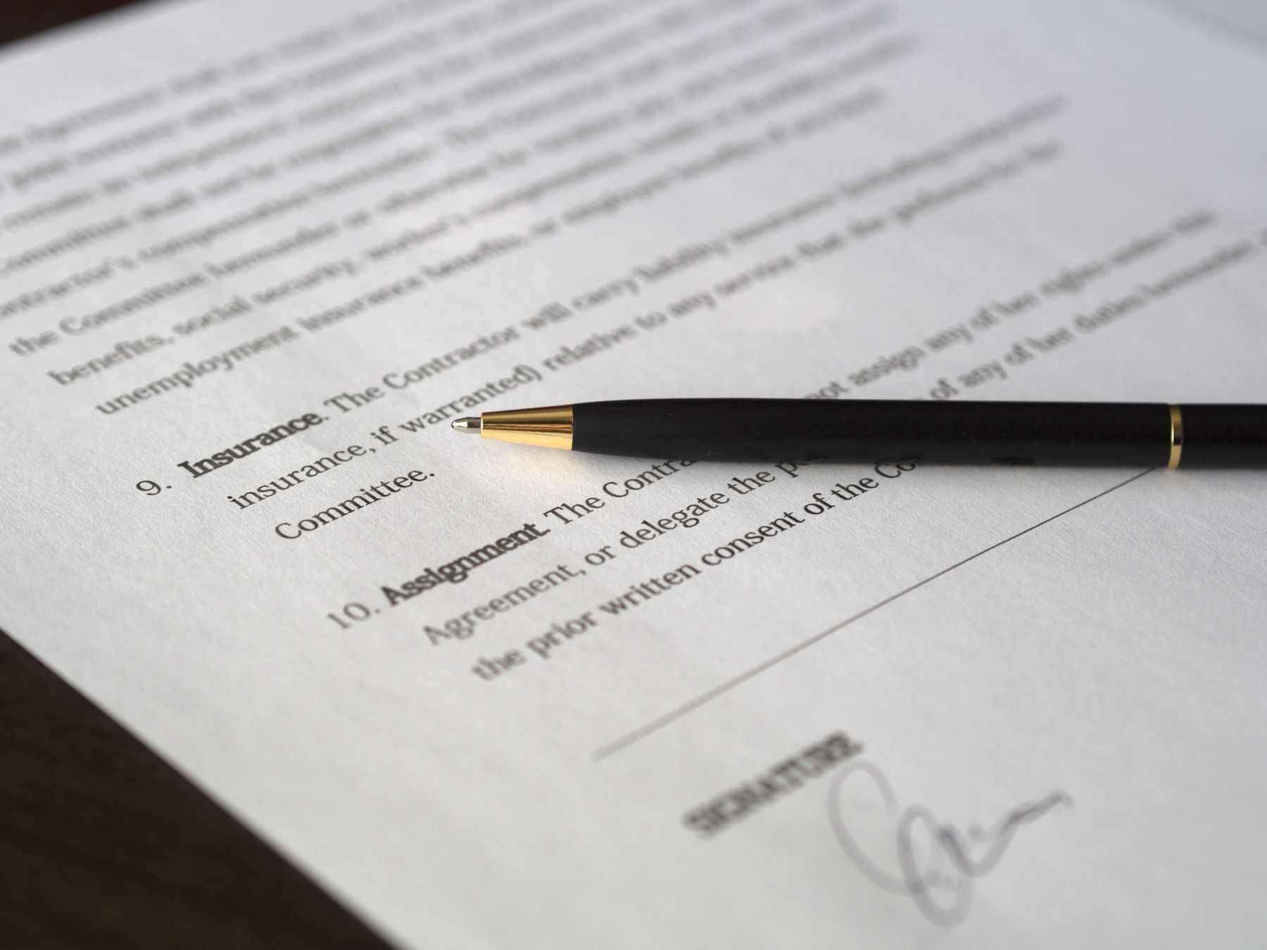 Contract tipărit cu un pix așezat pe pagină, lângă semnătură