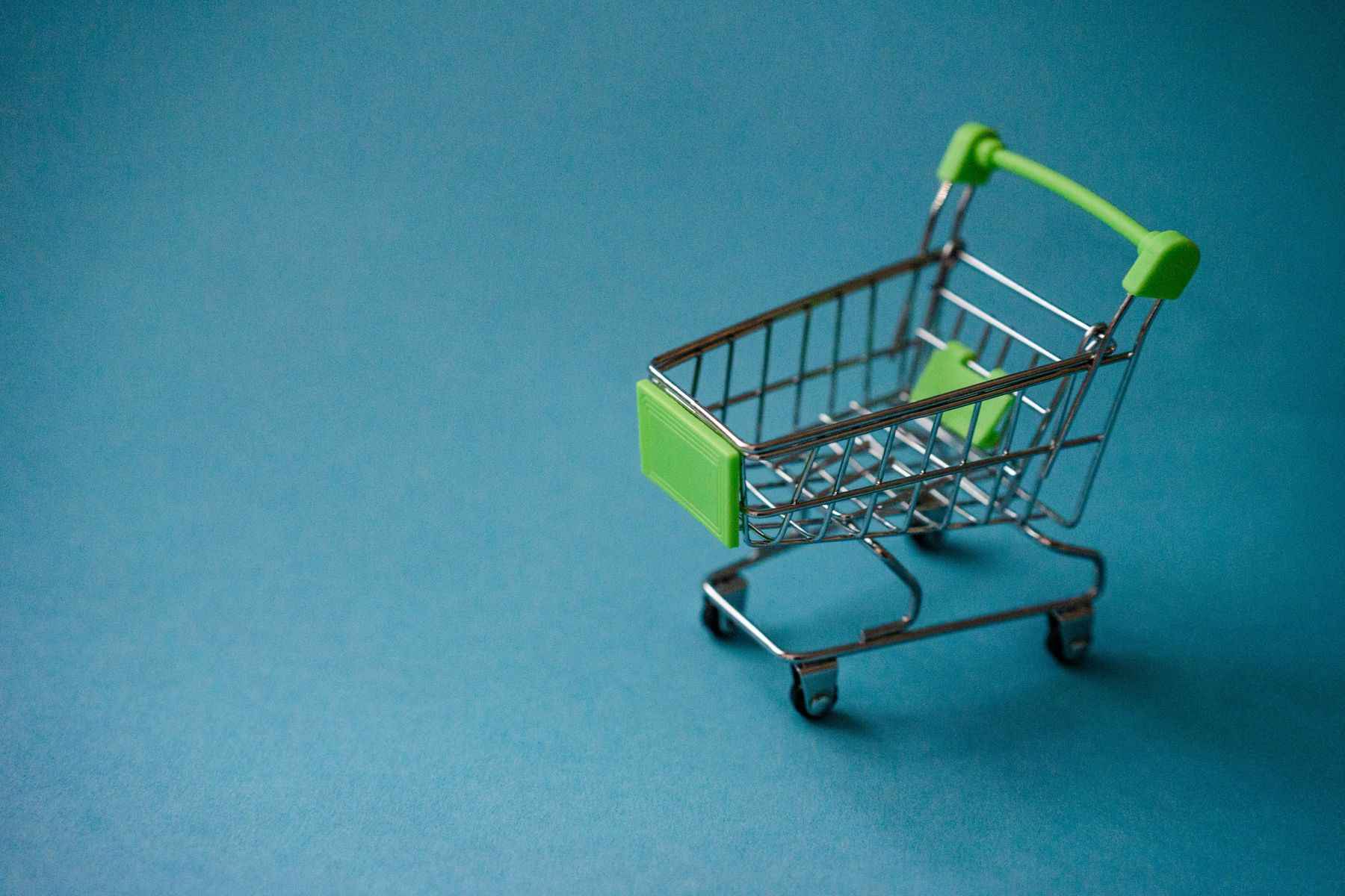 Coș de cumpărături în miniatură pe fundal albastru-turcoaz
