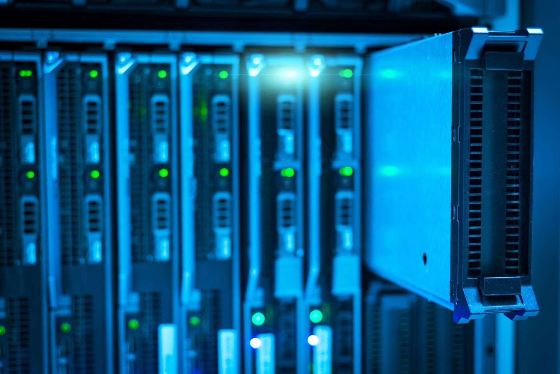 Servere blade montate în rack, în lumină albastră, cu un modul scos în față