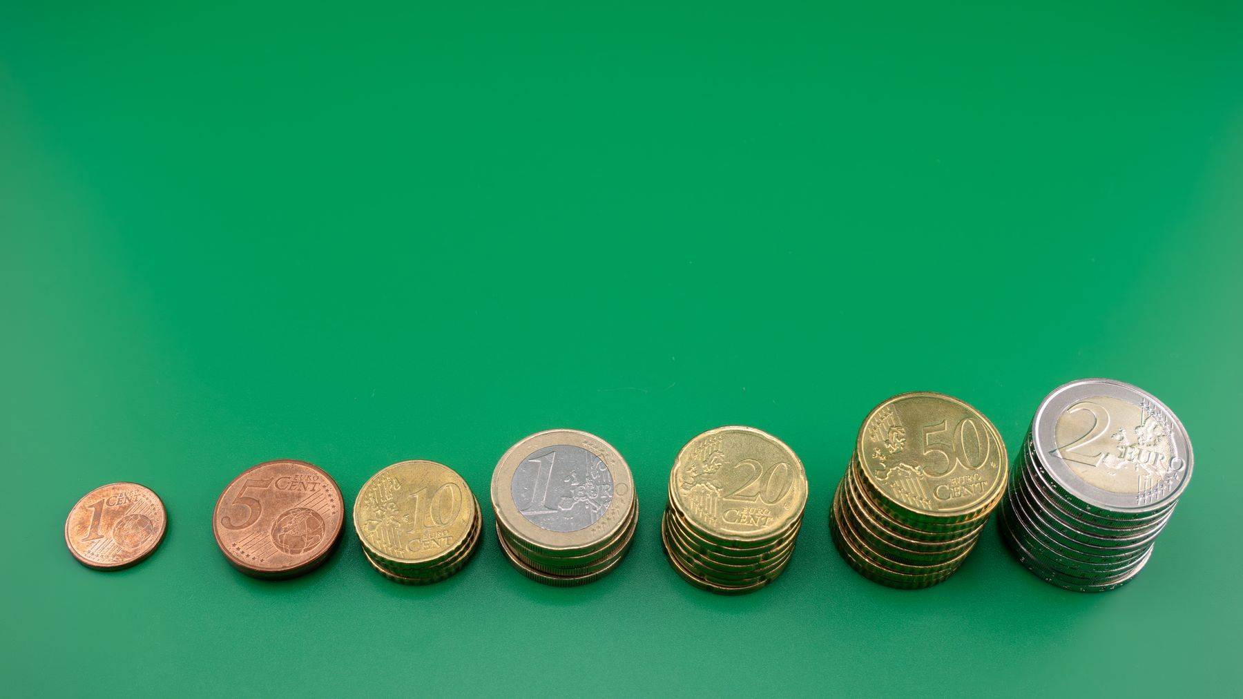 Monede euro așezate în ordine crescătoare pe un fundal verde