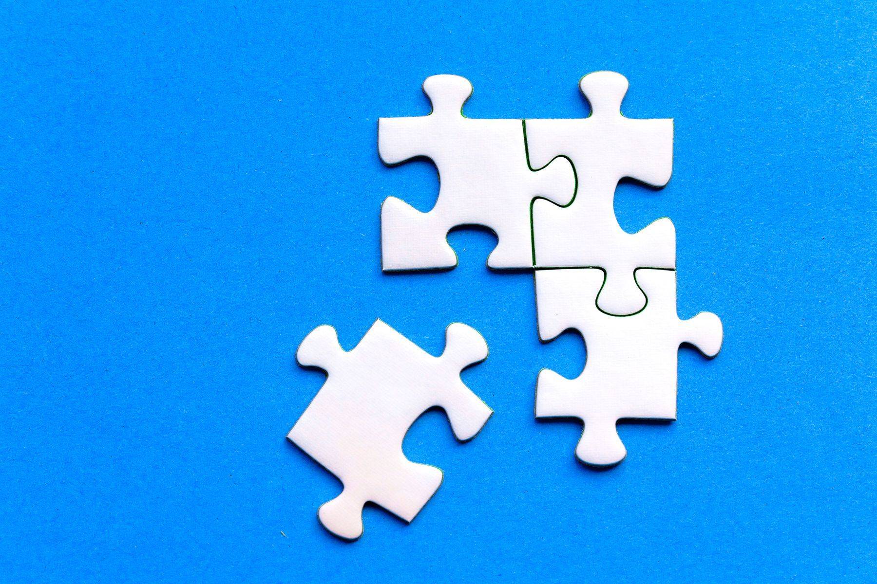 Piese albe de puzzle îmbinate, pe un fundal albastru