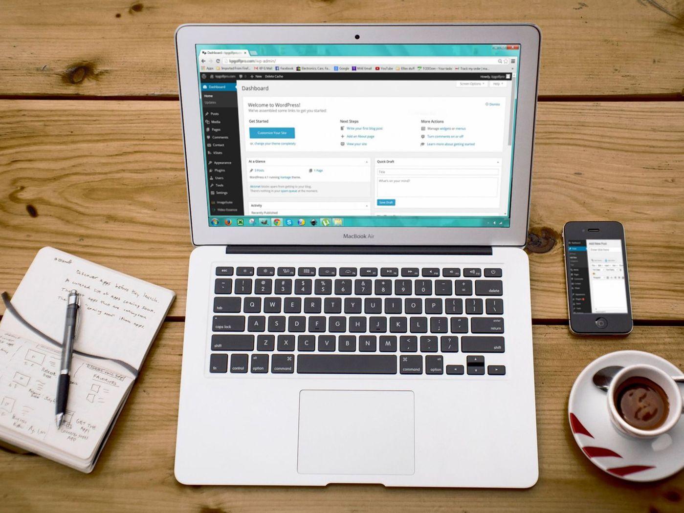 Laptop cu panoul de administrare WordPress deschis, lângă telefon, carnet și cafea