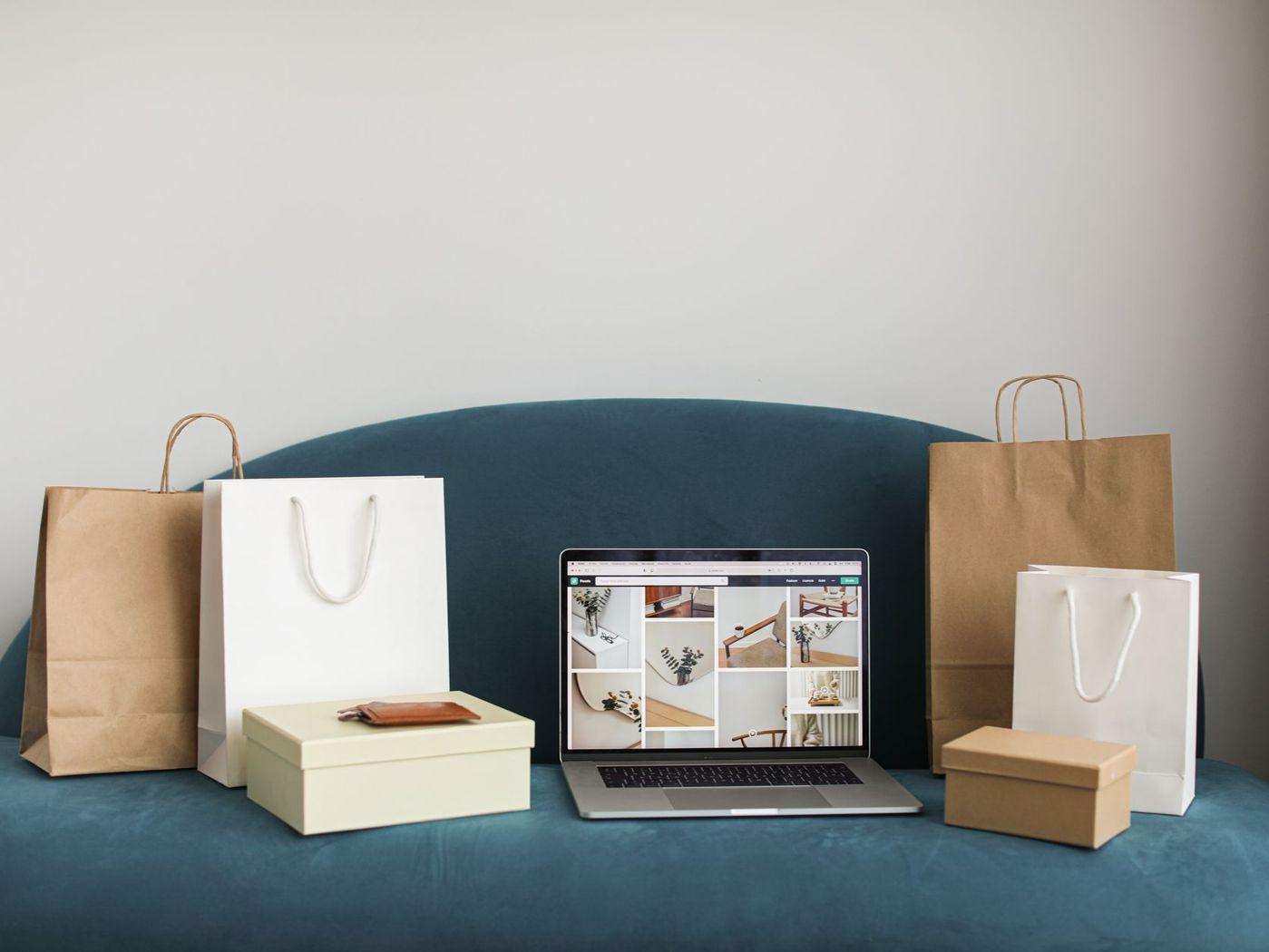Pungi de cumpărături și colete lângă un laptop cu un magazin online